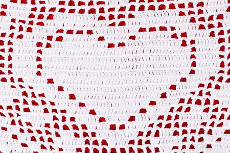 White lace doily with heart on red background, close up