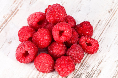 Red fruits of raspberry on wooden plank background, close up