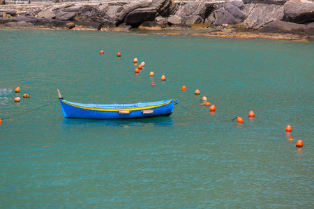 Moored blue boat in the marina, smooth water surface, background, Vernazza, Italy