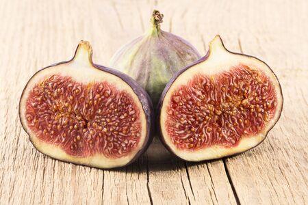 Fresh figs, half and whole on wooden plank, close up. Food photoの写真素材