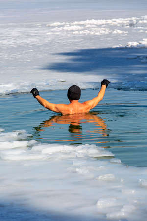Elderly man submerged in cold water while winter swimming in an ice hole of a frozen lake, Krakow, Polandの写真素材