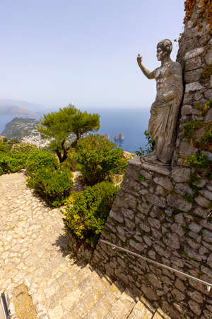 Capri Island; Italy - June 28; 2021: Aerial view from the top of the island Monte Solaro to the Tyrrhenian Sea with rocks Faraglioni; statue of Emperor Augustus in the foregroundのeditorial素材