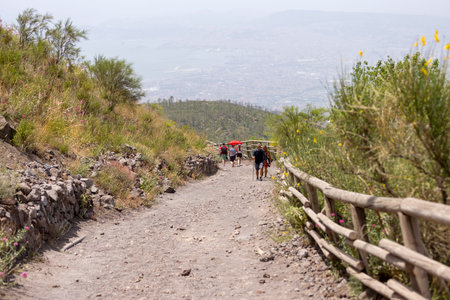 Mount Vesuvius, Italy - July 29, 2021: Tourists walking along the footpath to the top of Vesuvius volcano on a hot day. The path is made of sharp volcanic tuffのeditorial素材