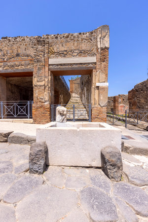Pompeii, Naples, Italy - June 26, 2021: Ruins of an ancient city destroyed by the eruption of the volcano Vesuvius in 79 AD near Naples. A fountain for public use on one of the streetsのeditorial素材