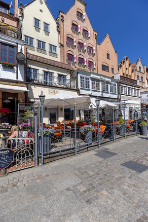 Gdansk, Poland - June 2, 2023: Outdoor restaurants in front of colorful historic tenement houses on...