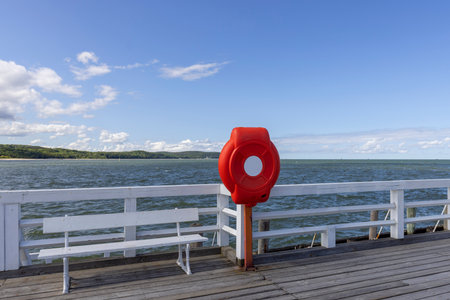 Sopot, Poland - June 2, 2023: Red lifebuoy on the barrier of Sopot pier in the Gulf of Gdansk in the Baltic Sea in sunny day. It is the longest wooden pier in Europe, 511.5 m longの写真素材