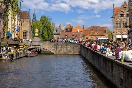 Bruges, Belgium - May 19, 2023: Crowd of people on the boulevard by the water channel Dijver Canal and on the Nepomucenus Bridge (Nepomucenusbrug)のeditorial素材