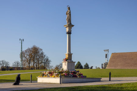 Czestochowa, Poland - October 18, 2024: Elderly woman in black praying on her knees in front of Monument to Our Lady Immaculate, Jasna Gora Monastery, famous pilgrimage centerのeditorial素材