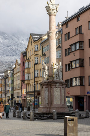 Innsbruck, Austria - February 26, 2023: View of city square, Maria Theresa Street with the Column of St. Anna. In the background snowcovered slopes of the Alps in cloudsのeditorial素材