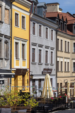 Lublin, Poland - May 24, 2022: Colorful historic tenement houses on Grodzka Street leading to Grodzka Gate. Restaurants with street gardens and outdoor umbrellasのeditorial素材