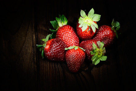 strawberry on a wooden table in the darkの写真素材
