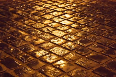 old cobblestone pavement after rain at nightの写真素材