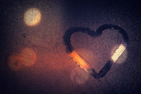 night city life through windowpane: darkness, rain and heartの写真素材