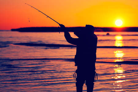 silhouette of a fisherman on the lake at sunsetの写真素材