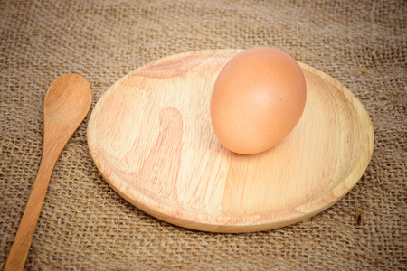 egg in wood plate on sack texture for vintage backgroundの写真素材