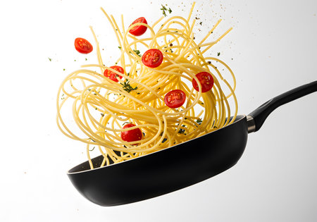 Spaghetti tossed in air with cherry tomatoes in a frying panの素材