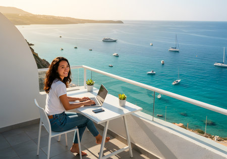 Digital nomad working with laptop on sunny terrace overlooking the sea with boatsの素材