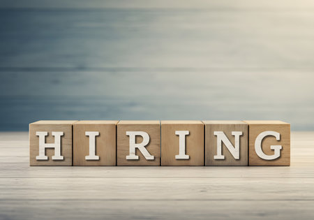 The word HIRING is spelled out on six wooden blocks set on a light wooden surface. This image is a visual symbol for recruitment, new jobs, employment, and career opportunities.の素材