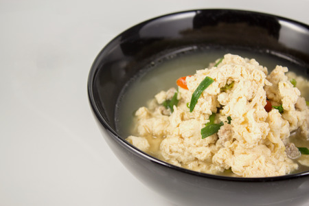 Fried Eggs in Clear Soup in black bowl on white backgroundの写真素材