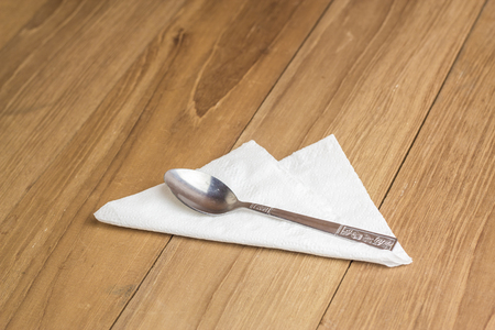 metal spoon over tissue paper on wooden boardの写真素材