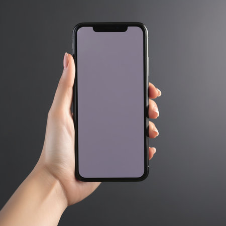 Female hand holding smartphone with blank screen on gray background. Mock upの素材
