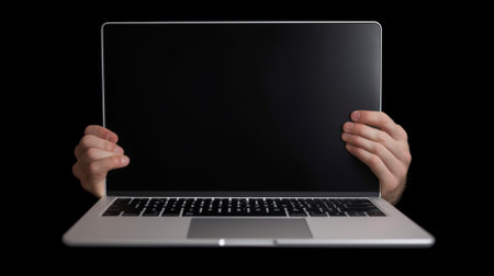 Hands holding a laptop with blank screen, isolated on black backgroundの素材