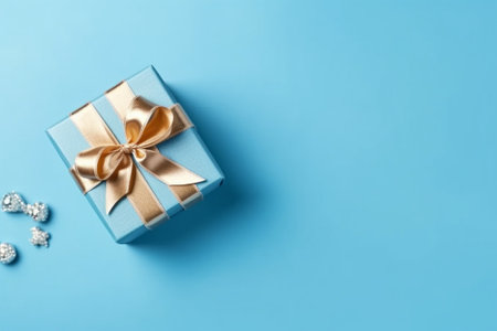 Gift box with golden bow on blue background. Flat lay, top view.の素材