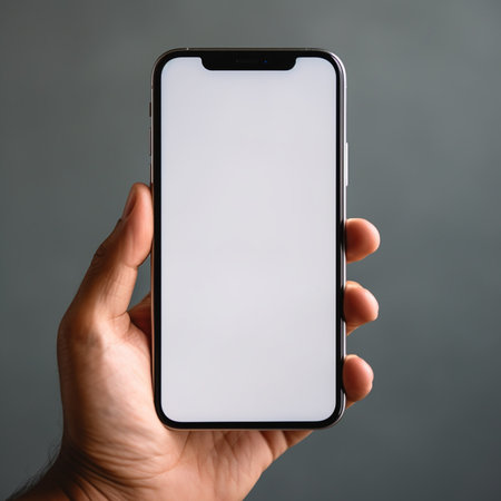 male hand holding a smartphone with a blank screen on a gray backgroundの素材