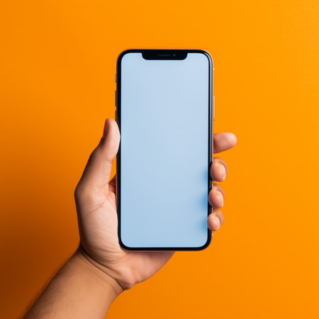 male hand holds a smartphone with a blank screen on an orange backgroundの素材