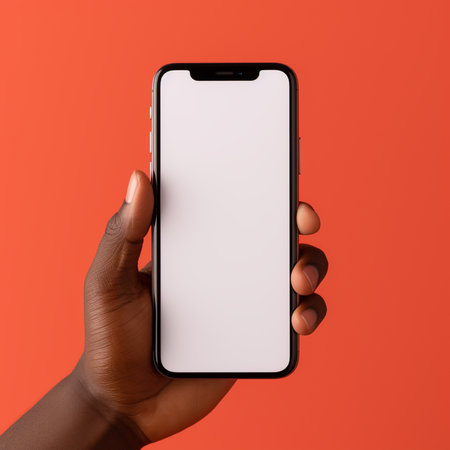 Black female hand holding smartphone with blank screen on orange background. Mock upの素材