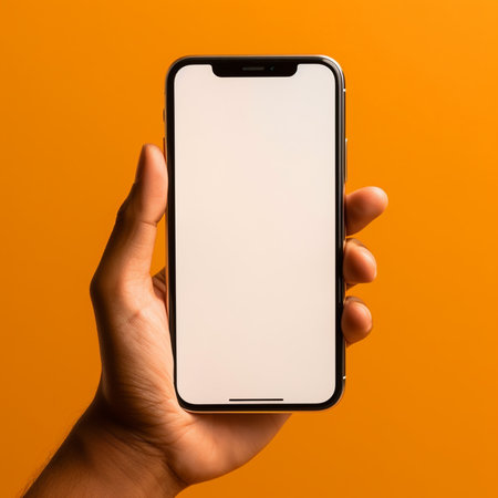 male hand holding a smartphone with a blank screen on an orange backgroundの素材