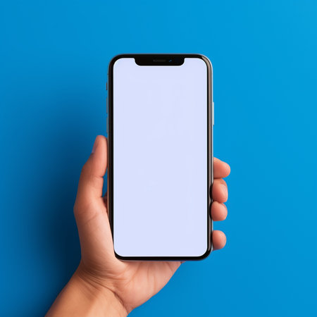 Female hand holding smartphone with blank screen on blue background, mockupの素材