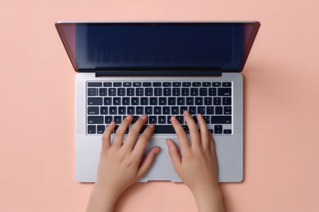 Female hands typing on laptop keyboard on pastel pink background, top viewの素材