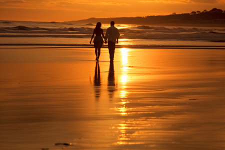Silhouette of a couple walking on the beach at sunset.の素材