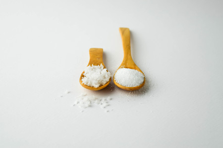 salt and sugar on small wooden spoon on white backgroundの写真素材