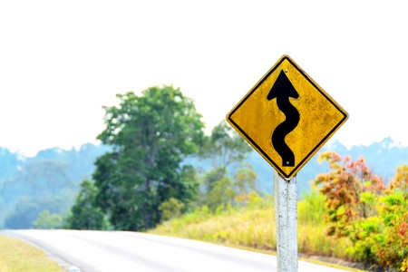 winding road sign in yellowの写真素材