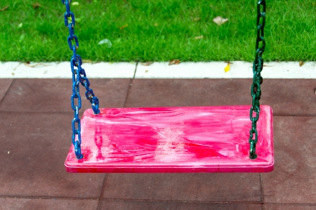 Empty swing set on red floor backgroundの写真素材