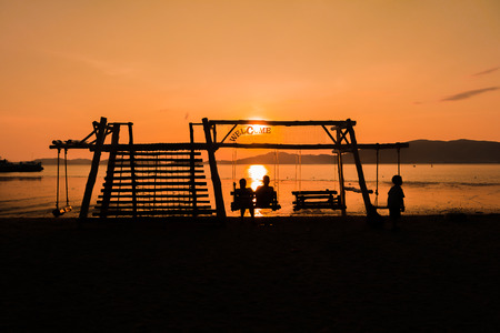 Silhouette of a family enjoying swing at sunset beachの写真素材