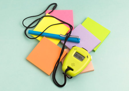 Time management concept. Top view of composition with a stopwatch,a pen and colorful empty sticky...
