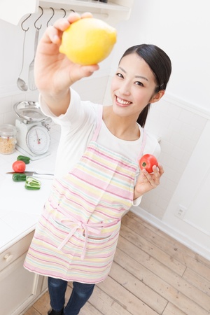 Young Asian woman with vegetables in the kitchenの写真素材