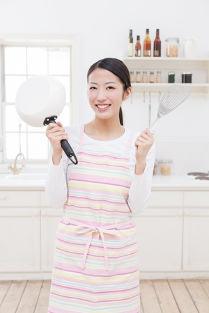 Young Asian woman with cooking utensils in the kitchenの写真素材