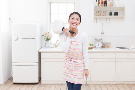 Young Asian woman with cooking utensils in the kitchenの写真素材