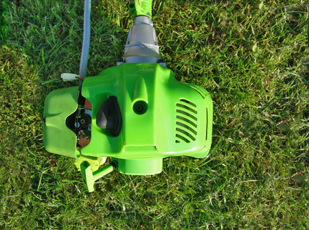 engine power trimmer gasoline mower lies in the village on the grass after mowing the grass