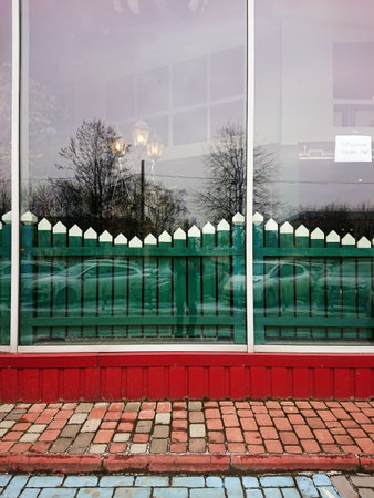 In winter, the cobblestone house has large windows reflecting the trees of a car and a man