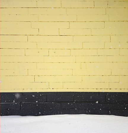yellow background with black and white brick wall with snow