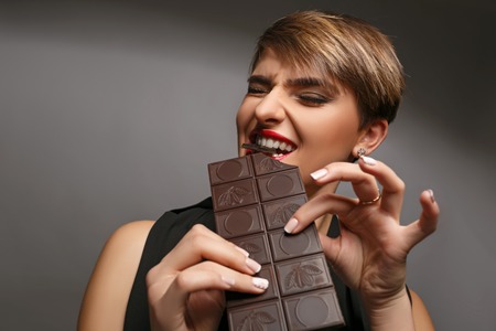 Portrait of a beautiful woman   that is a real chocolate fan on a grey background.の写真素材
