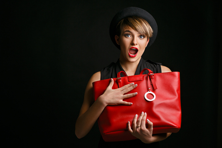 Close up of a beautiful woman with a  good sense of humor , holding her  fancy red bag.の写真素材