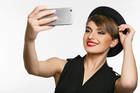 A portrait of a very attractive young  lady making  selfie in a photo studio.の写真素材