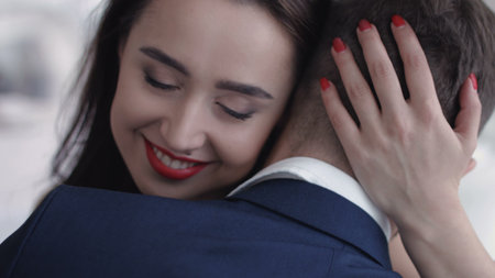 Young couple embrace and hold each other. Girl looks wistful and a little sad.
