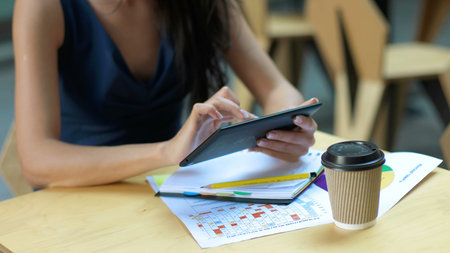 Working at the cafe. Young beautiful long hair woman sitting at the table and using tablet computer...